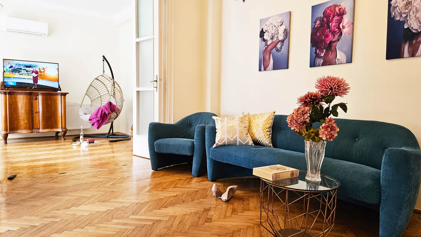 The bright BudaSmile 4 living room with a blue sofa, parquet floor and hanging chair