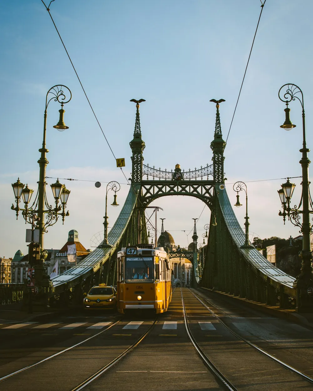 A yellow tram on Liberty Bridge, with the dome of the Gellért Baths on the far bank